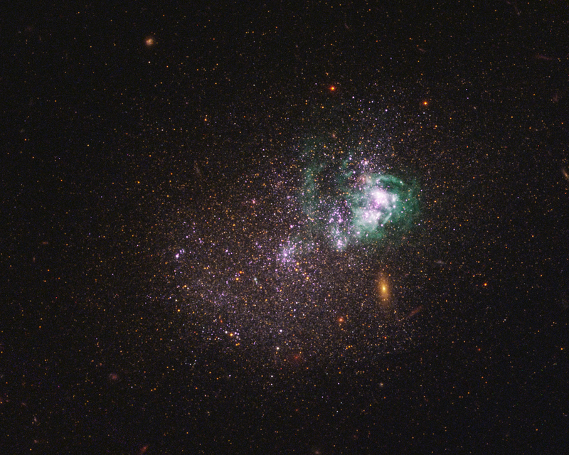 UGCA 281, a blue compact dwarf galaxy. Within it, two giant star clusters appear brilliant white and are swaddled by greenish hydrogen gas clouds.